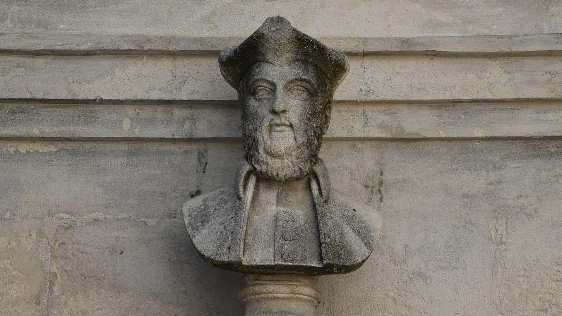 Stone sculpture of Nostradamus as a bust, set against a weathered wall