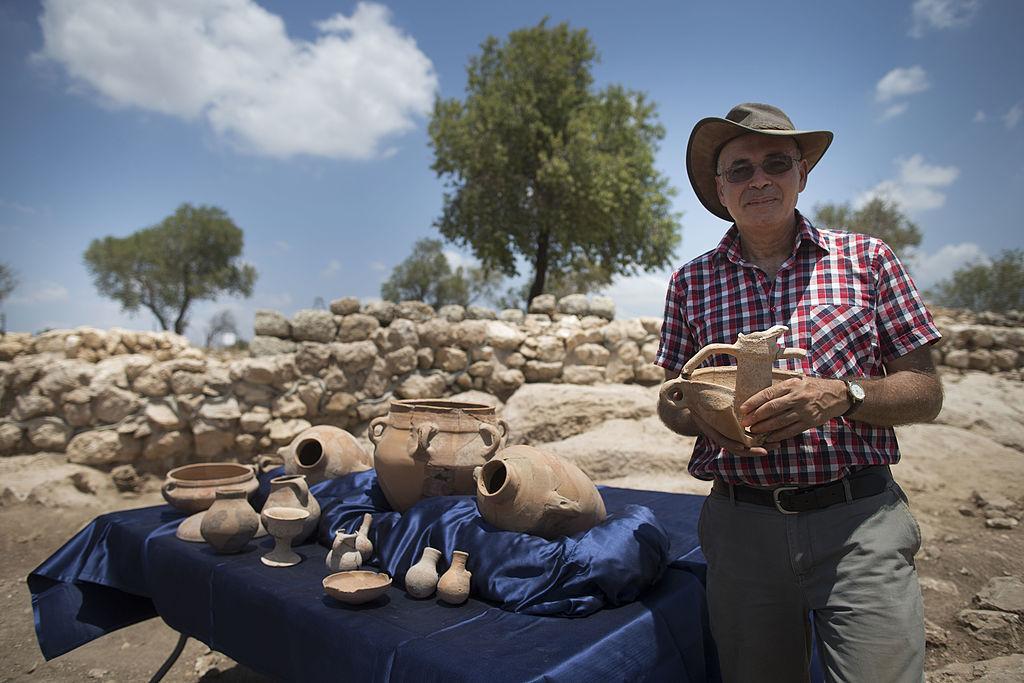 Professor Yosef Garfinkel holds an article from his archaeological excavation next to the remains of what is thought to be King David's palace