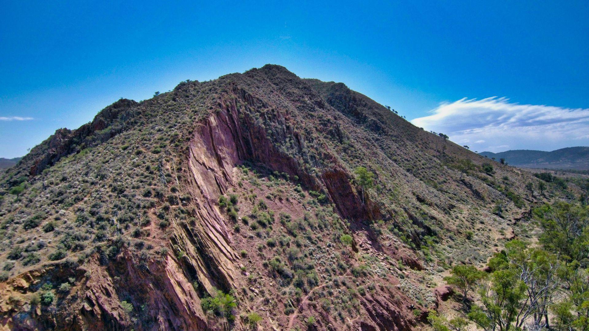 A brown, rocky mountain in Flinders Ranges, South Australia, under a blue sky in the daytime.