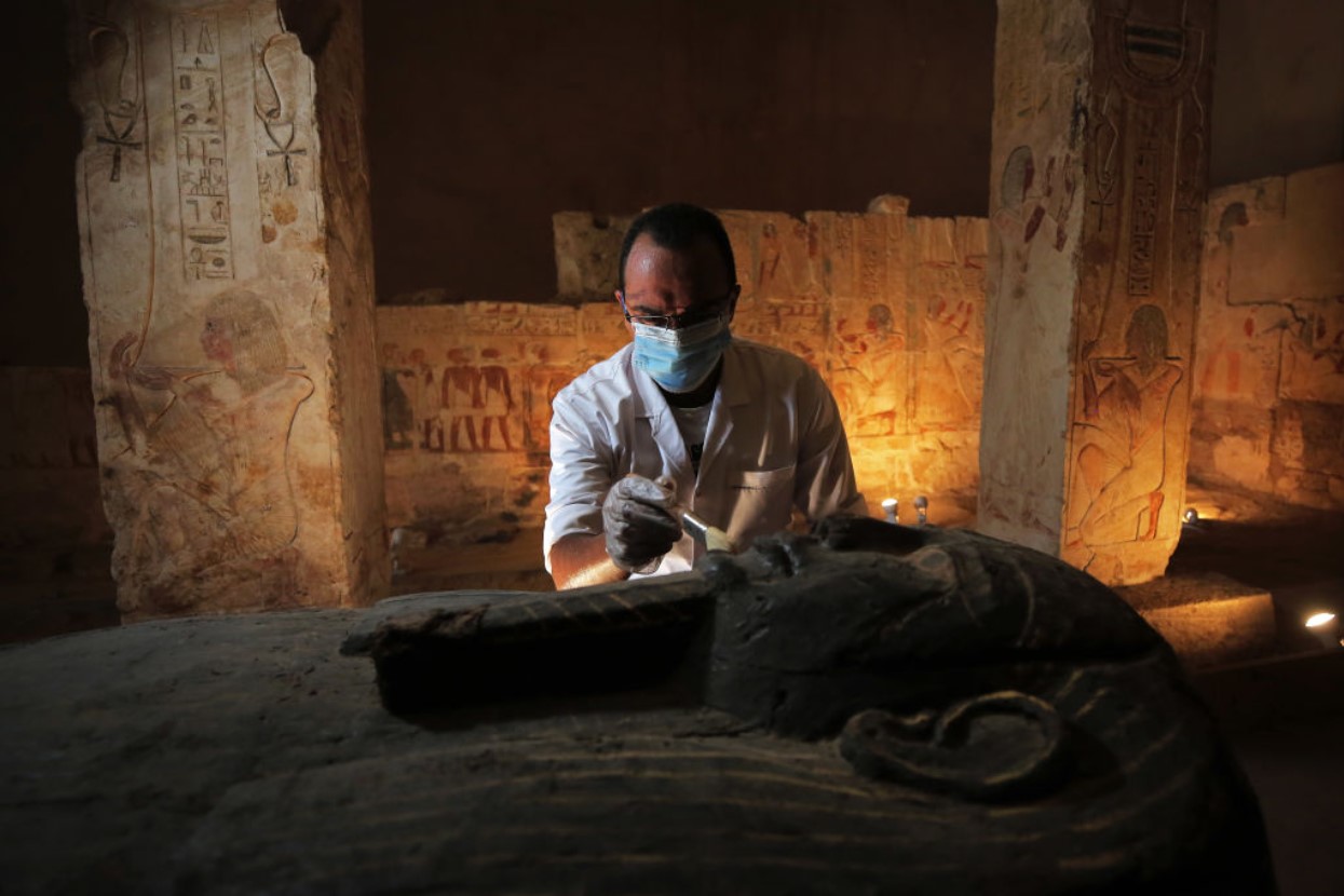 An archeologist wars a mask on an archaeological discovery on October 3, 2020 in Cairo, Egypt