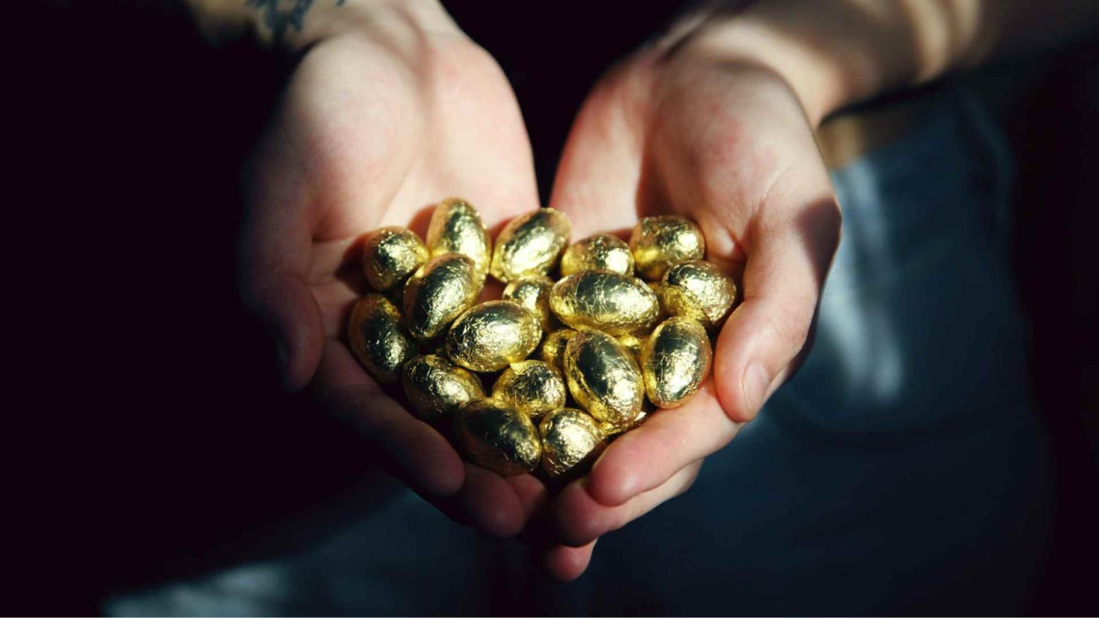 A person holding gold pieces in their open hands.
