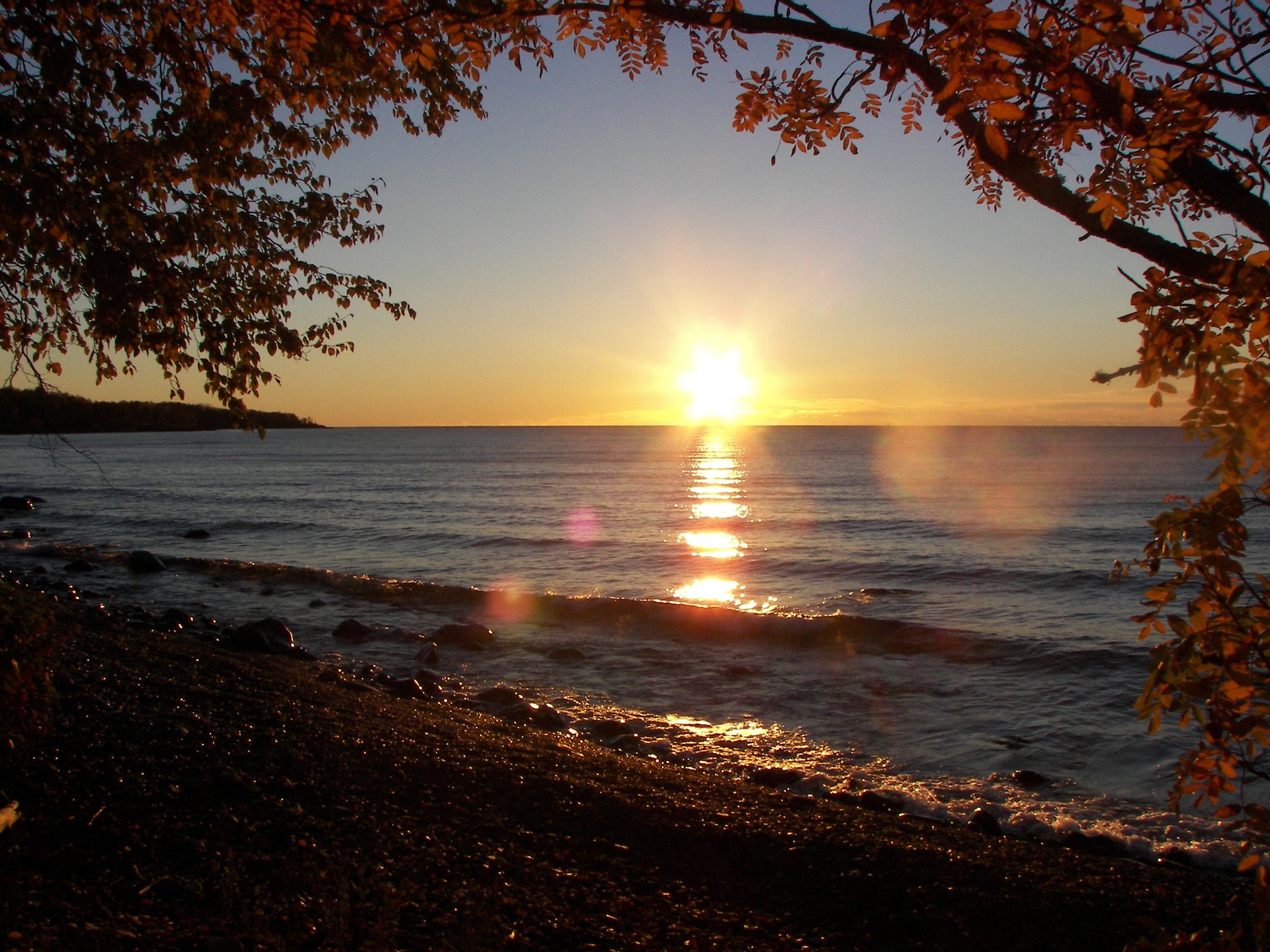 A sunrise over a large lake in the summer froma rocky beach