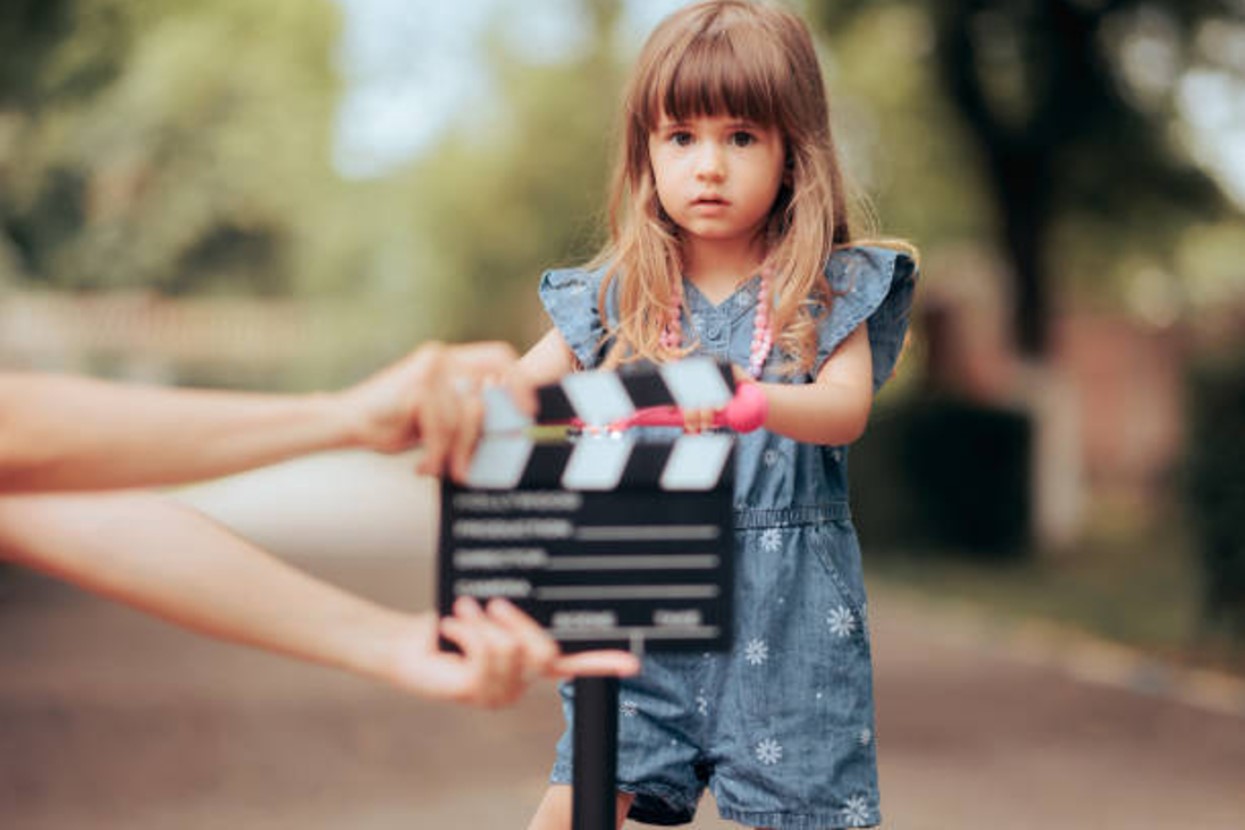 Young child actor stands in front of a clapperboard