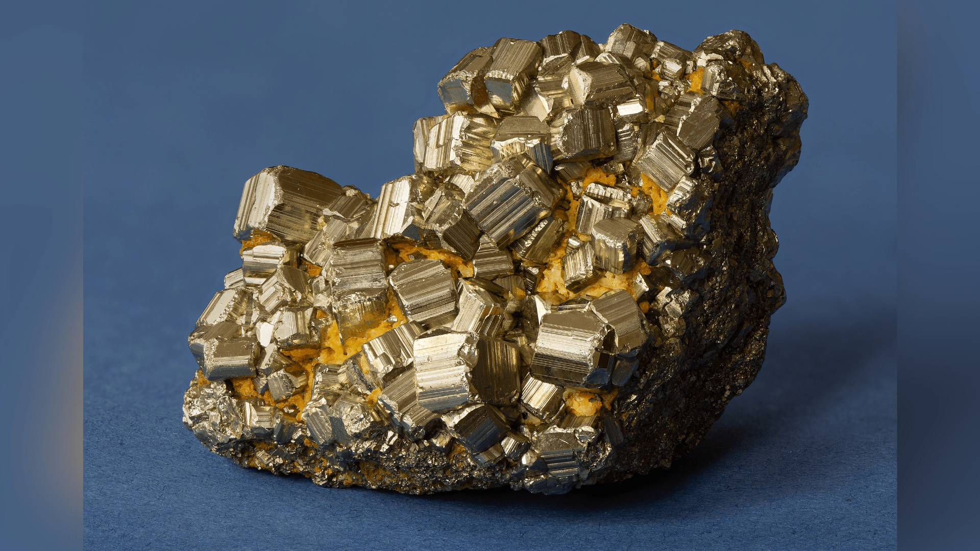 A rock of iron pyrite, or fool's gold), sitting against a blue background.