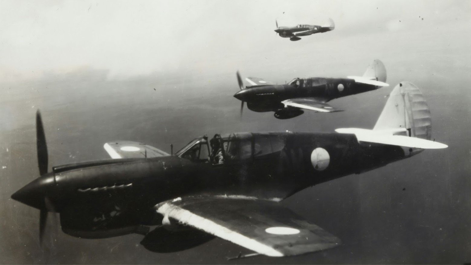 A black and white photo of three airplanes in the sky during World War II.