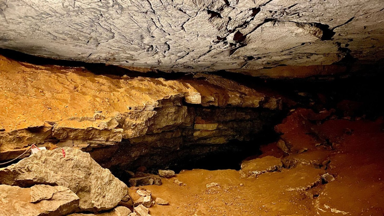 Image showcasing the interior of a cave with a low ceiling and layered rock formations