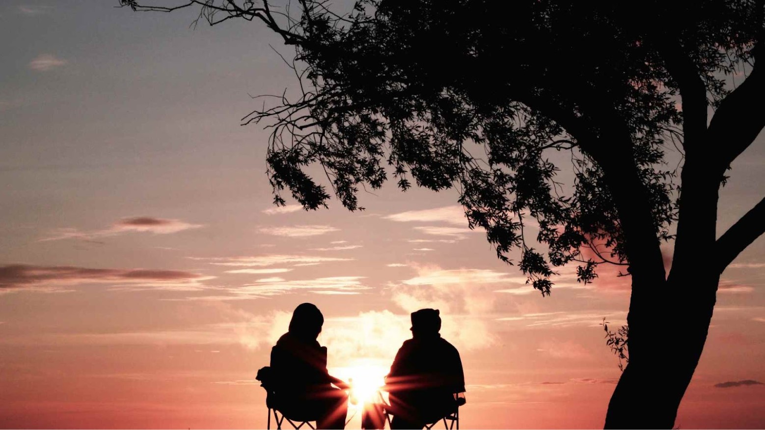 Two people enjoying one another’s company in front of a sunset.
