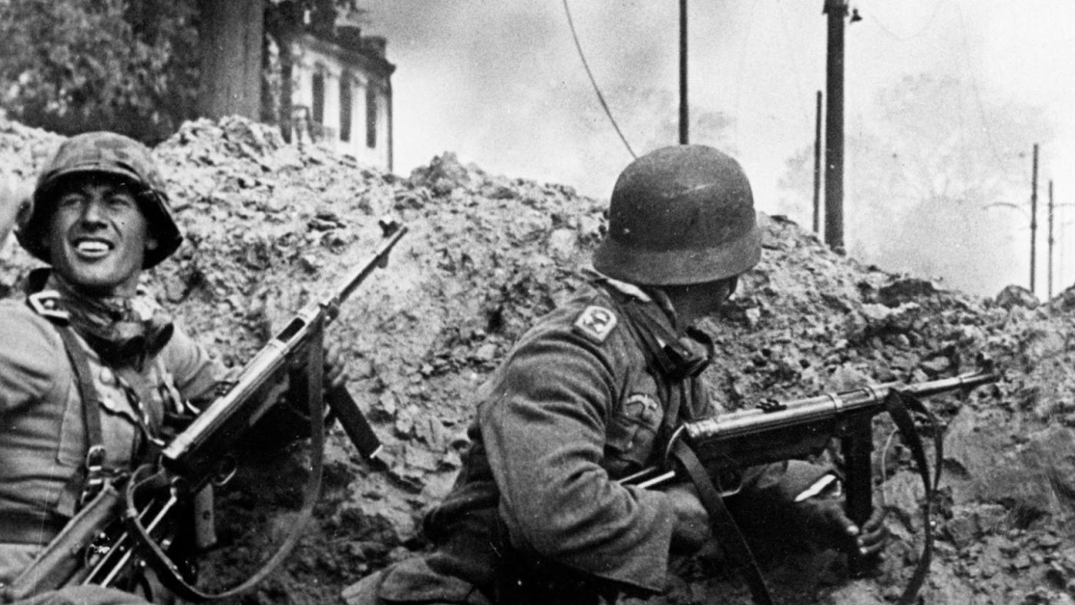 A black and white photo of two German soldiers with guns in a city trench during the Battle of Stalingrad during World War II.
