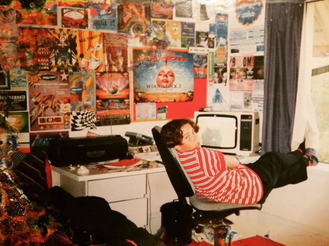 Young boy in the 90s sitting in his room covered in posters watching TV