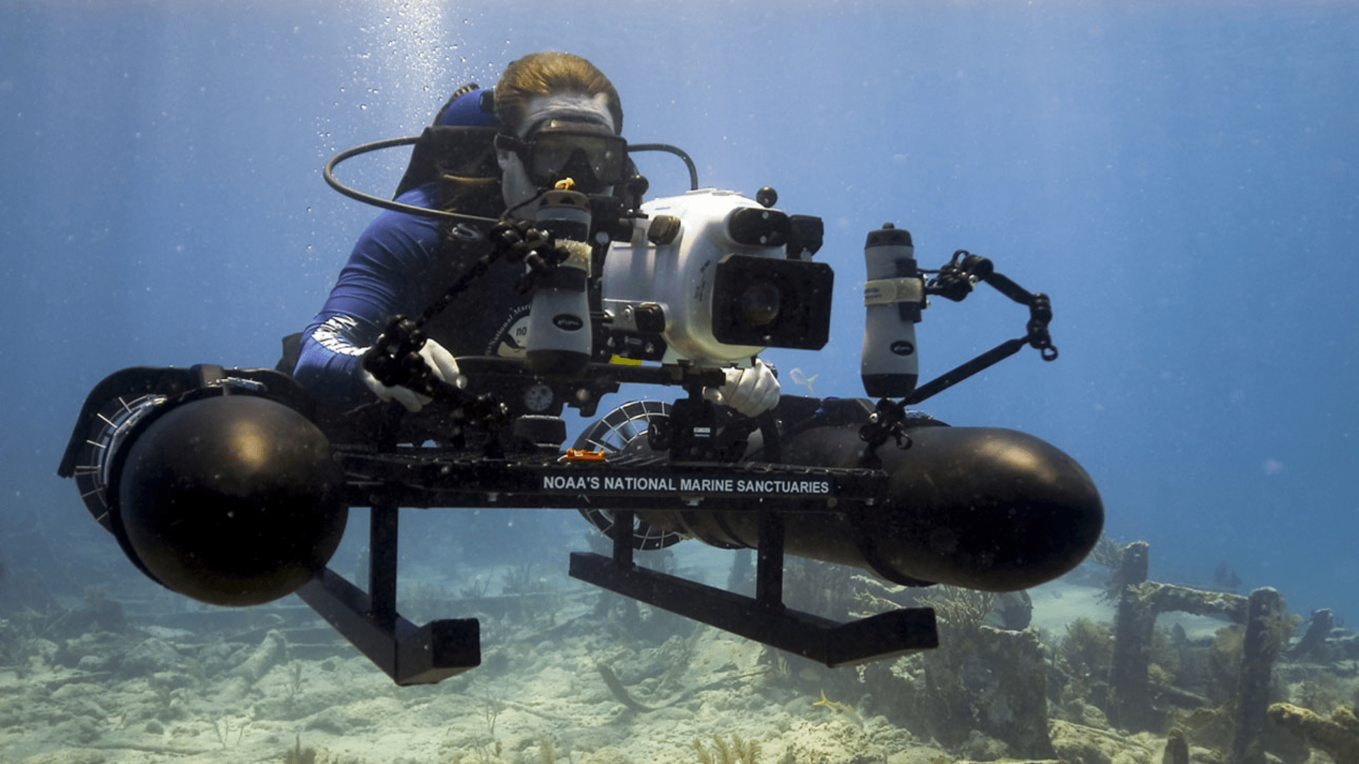A modern-day underwater archaeologist using a mounted sled and high-resolution camera to photograph a marine sanctuary.