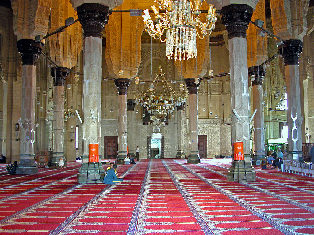 A room with red carpet and an chandelier hanging in the Abu al-Abbas al-Mursi Mosque Inside