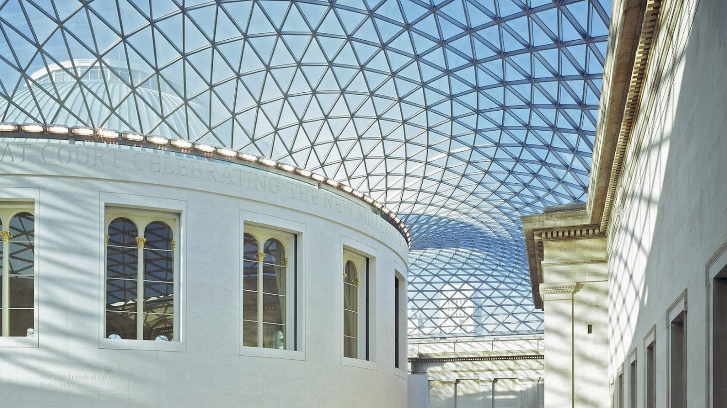 A view of the interior of the Great Court of the British Museum with a glass roof and metal beams