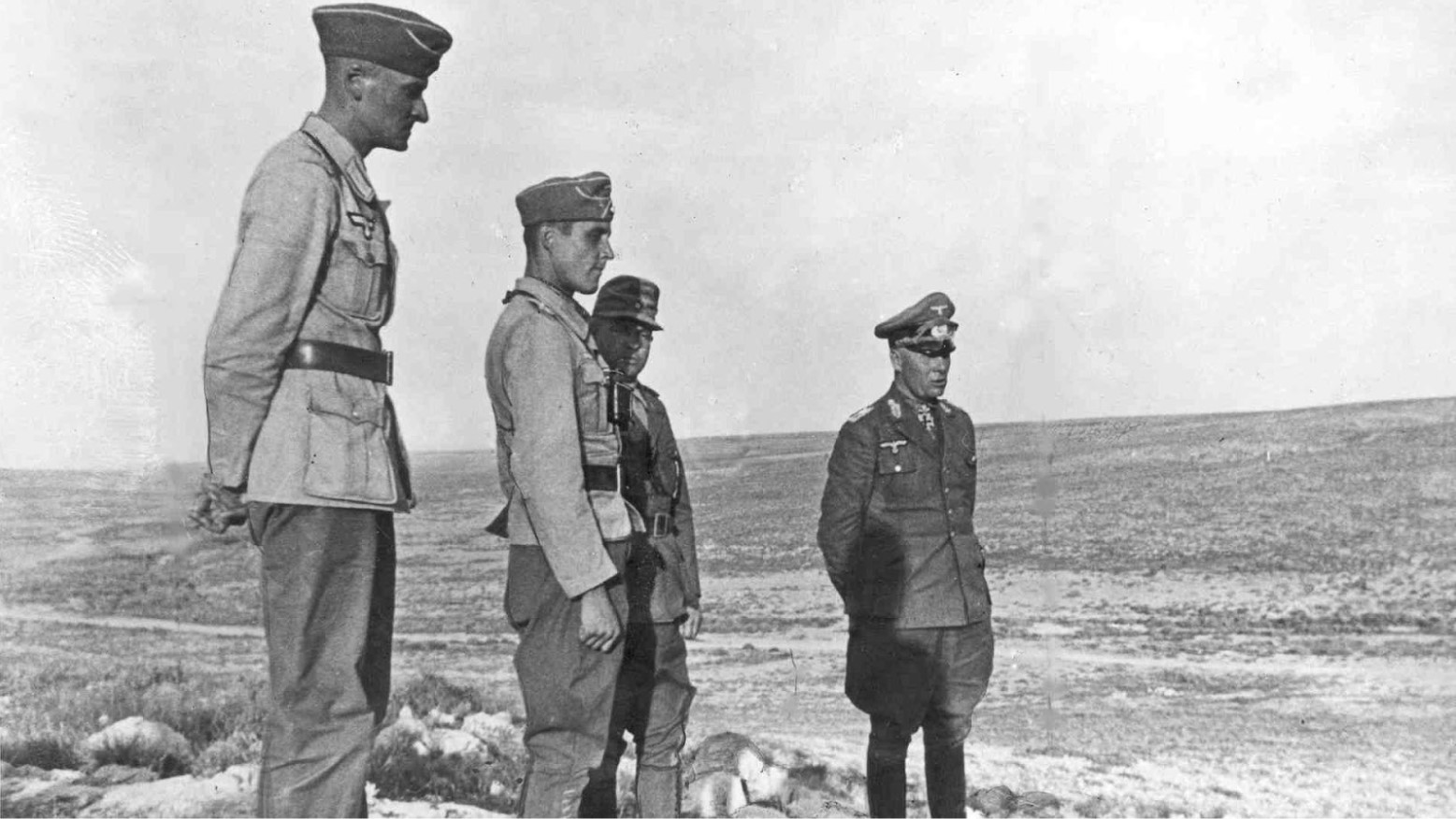 General Erwin Rommel standing next to a soldier in an open field.