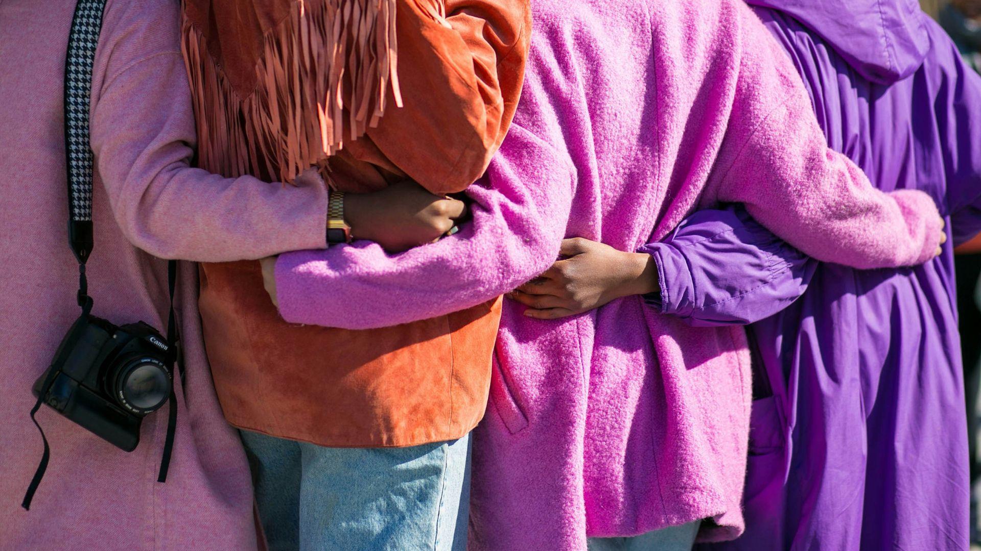 A close-up of four people embracing each other while wearing colorful coats.