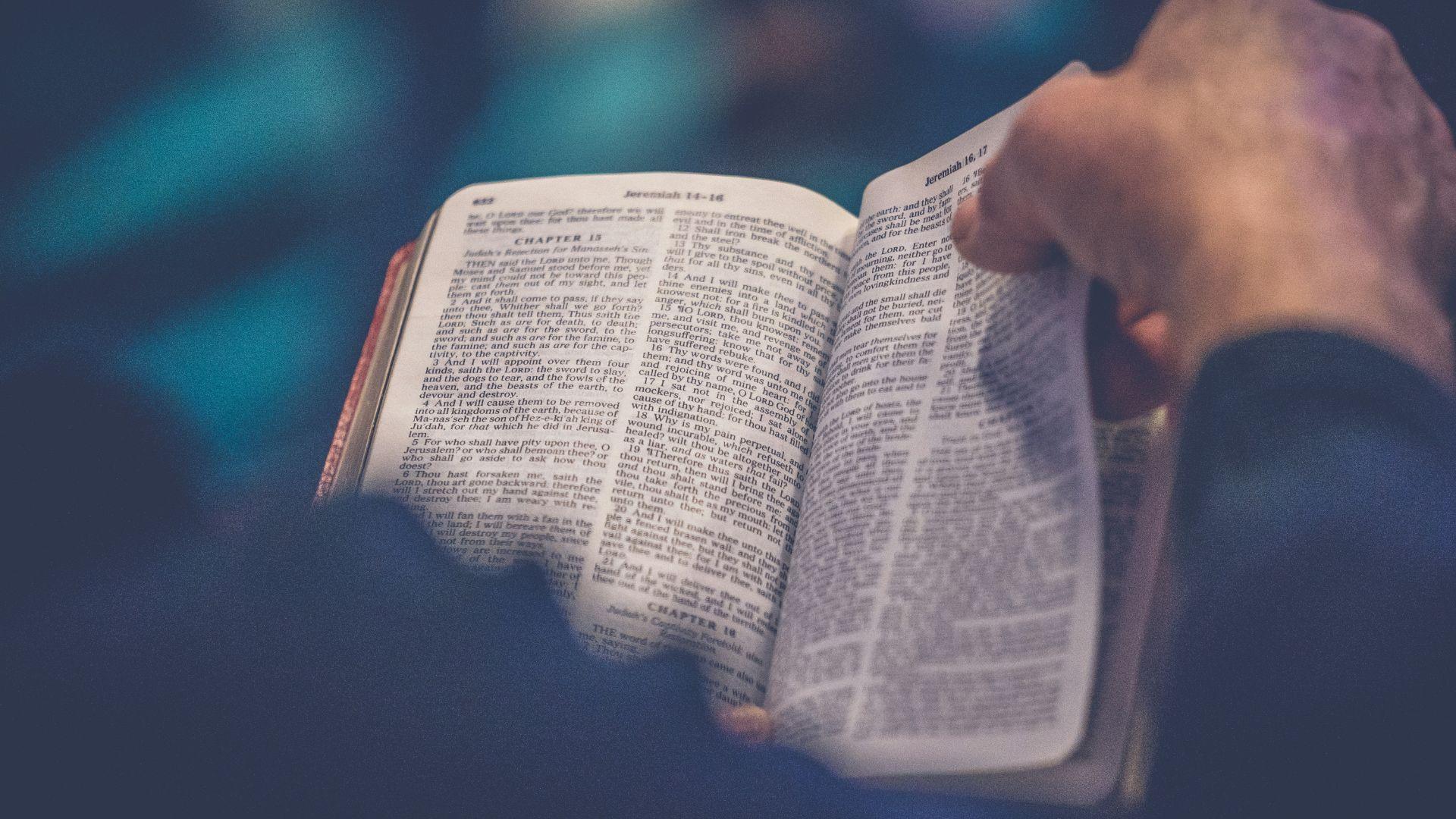 A person reading a Bible and flipping the page.