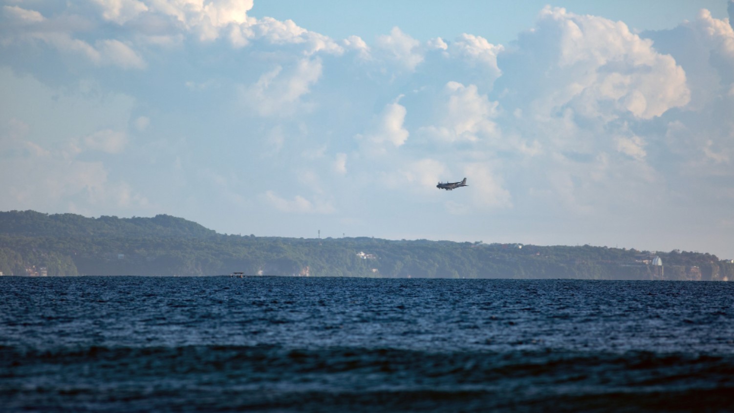An image of a large plane flying over the ocean