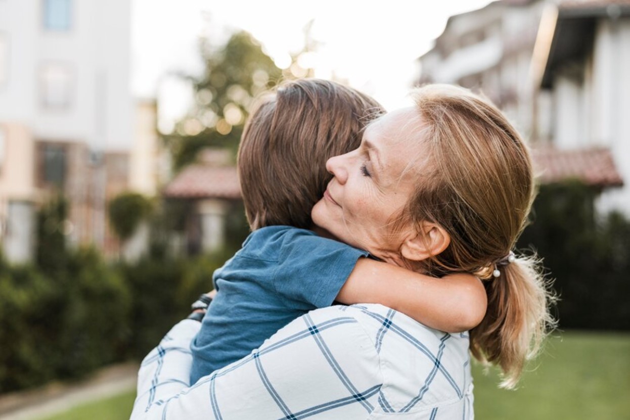 A mother closes her eyes while hugging her young son