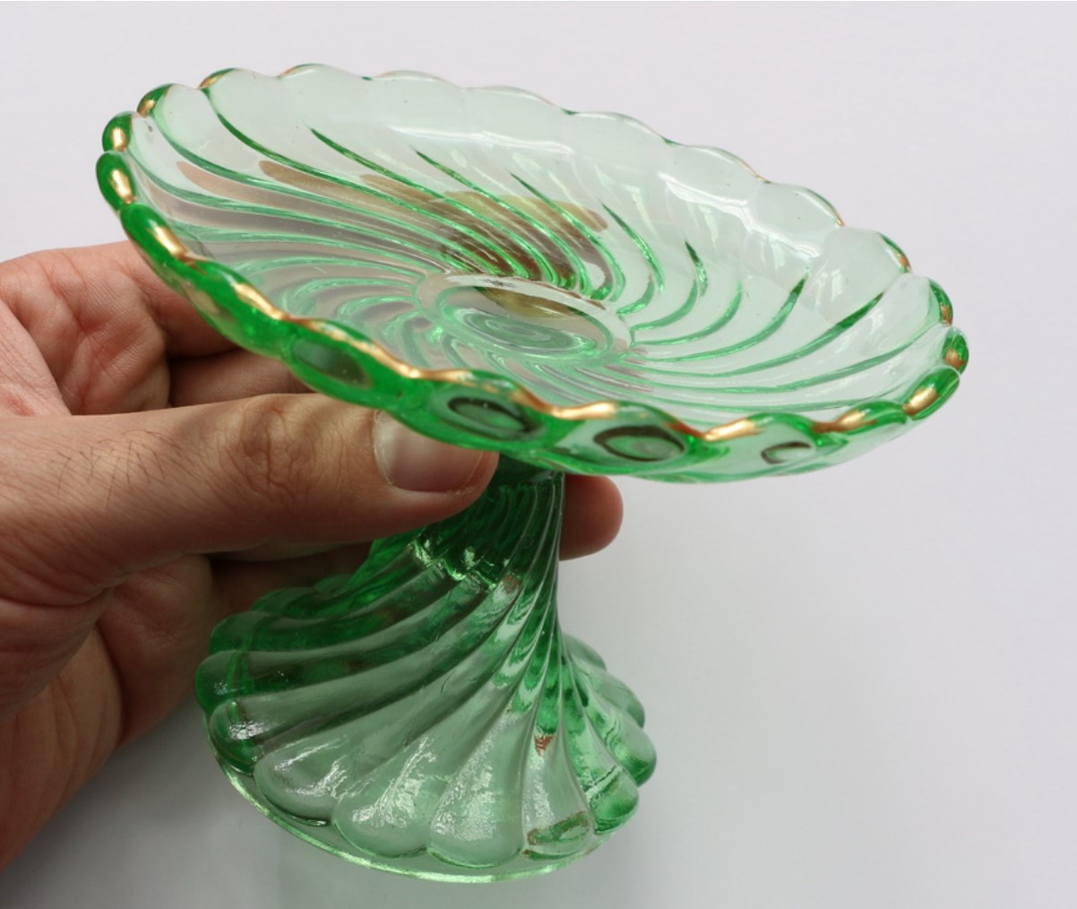 A woman is pictured holding a small item made from uranium glass