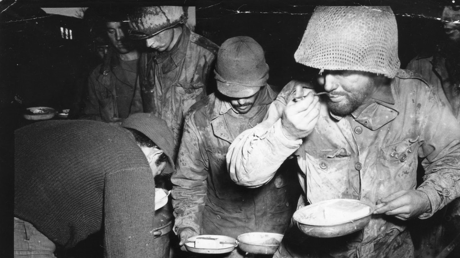 A black and white WWII-era photo of American soldiers eating.