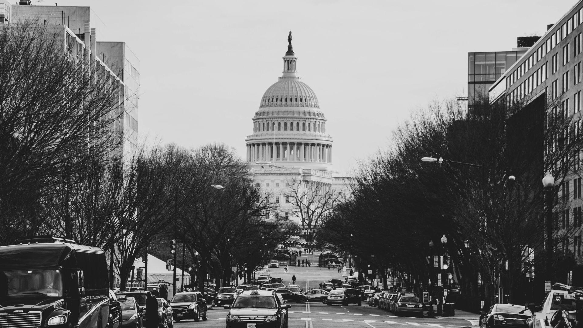 A black and white photo of a street in front of the U.S. Capitol building.