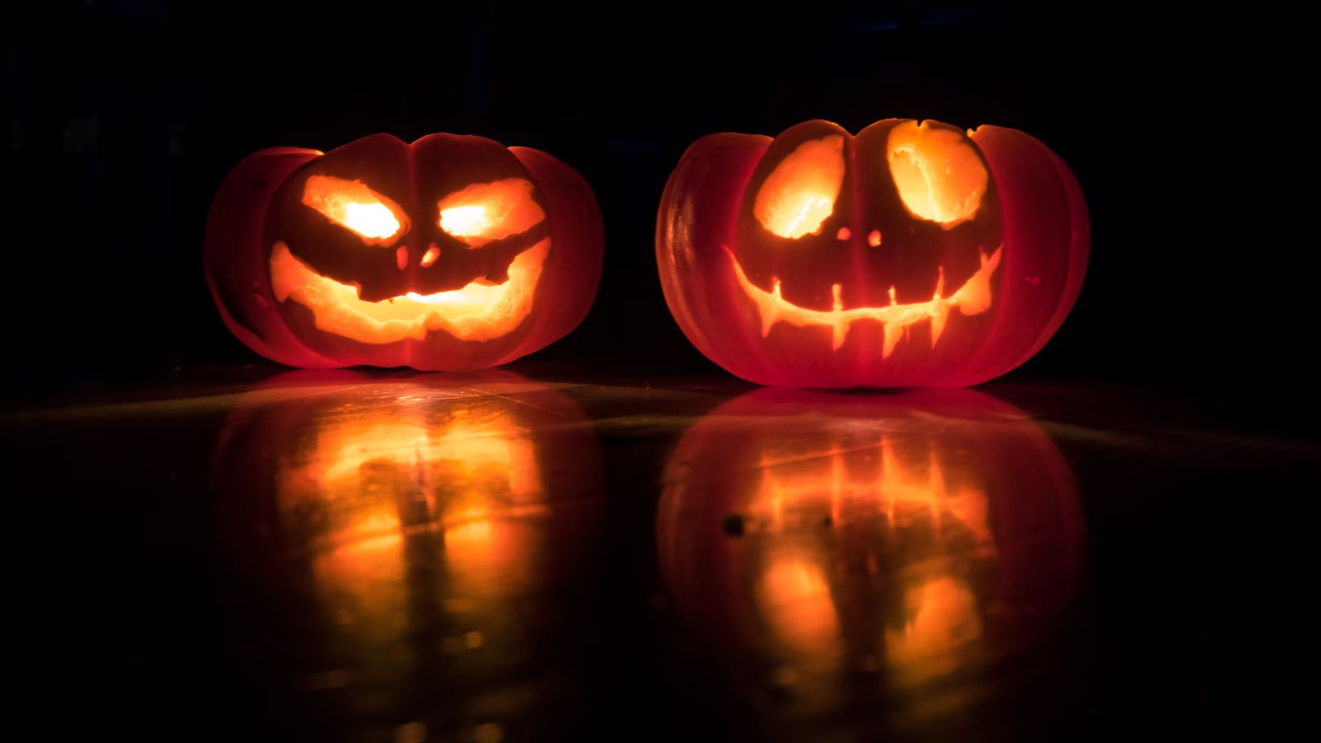 Two pumpkins carved for Halloween. Both have scary faces consisting of two eyes and a mouth.