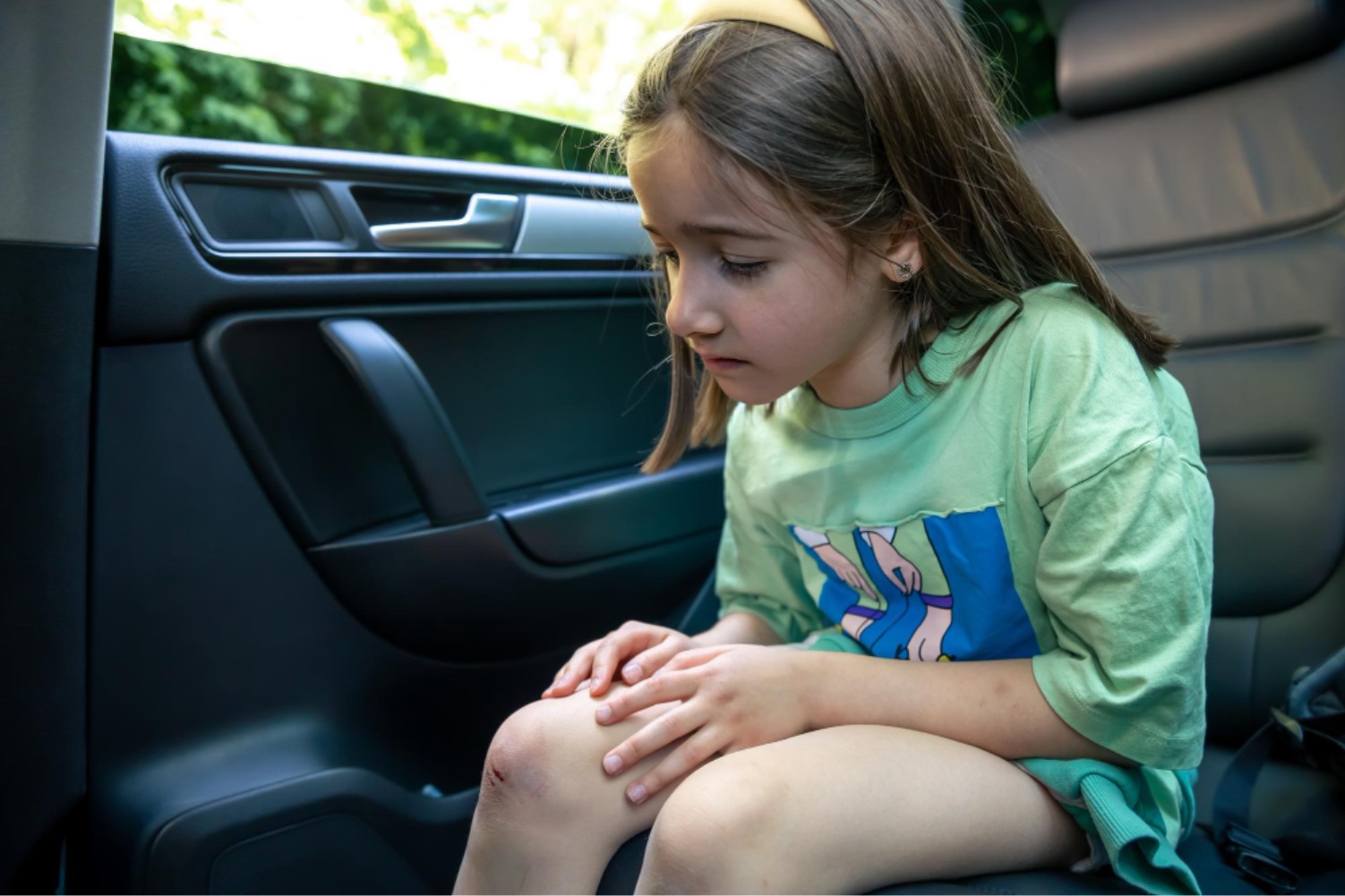A young child is pictured in the back seat of a car without a seatbelt