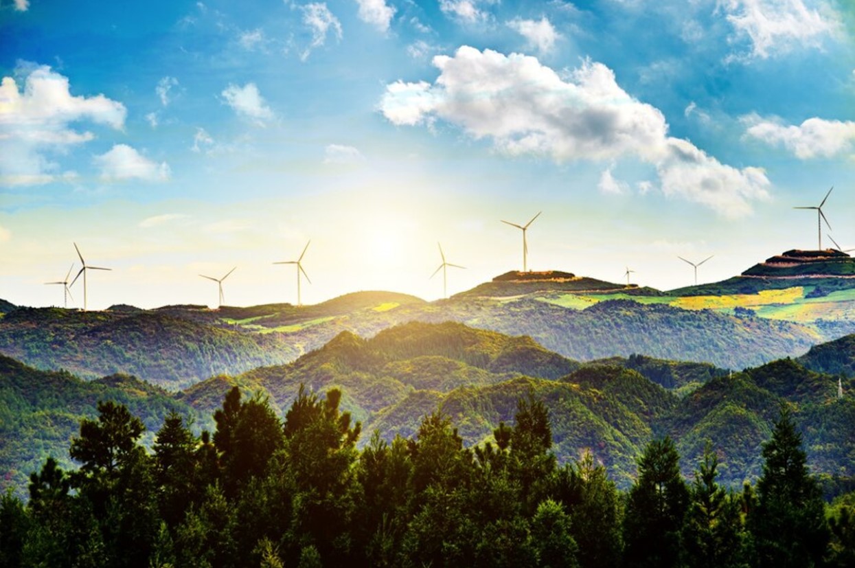 A wind farm along a forested mountain range