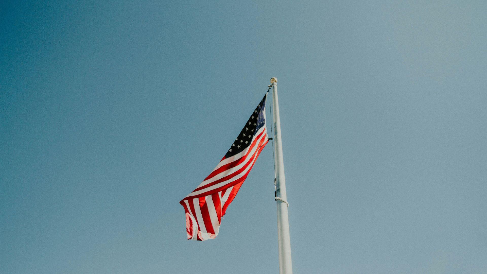 The American flag on a pole against a clear blue sky.