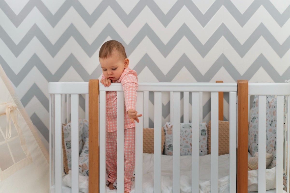 A baby is pictured standing up inside her white crib