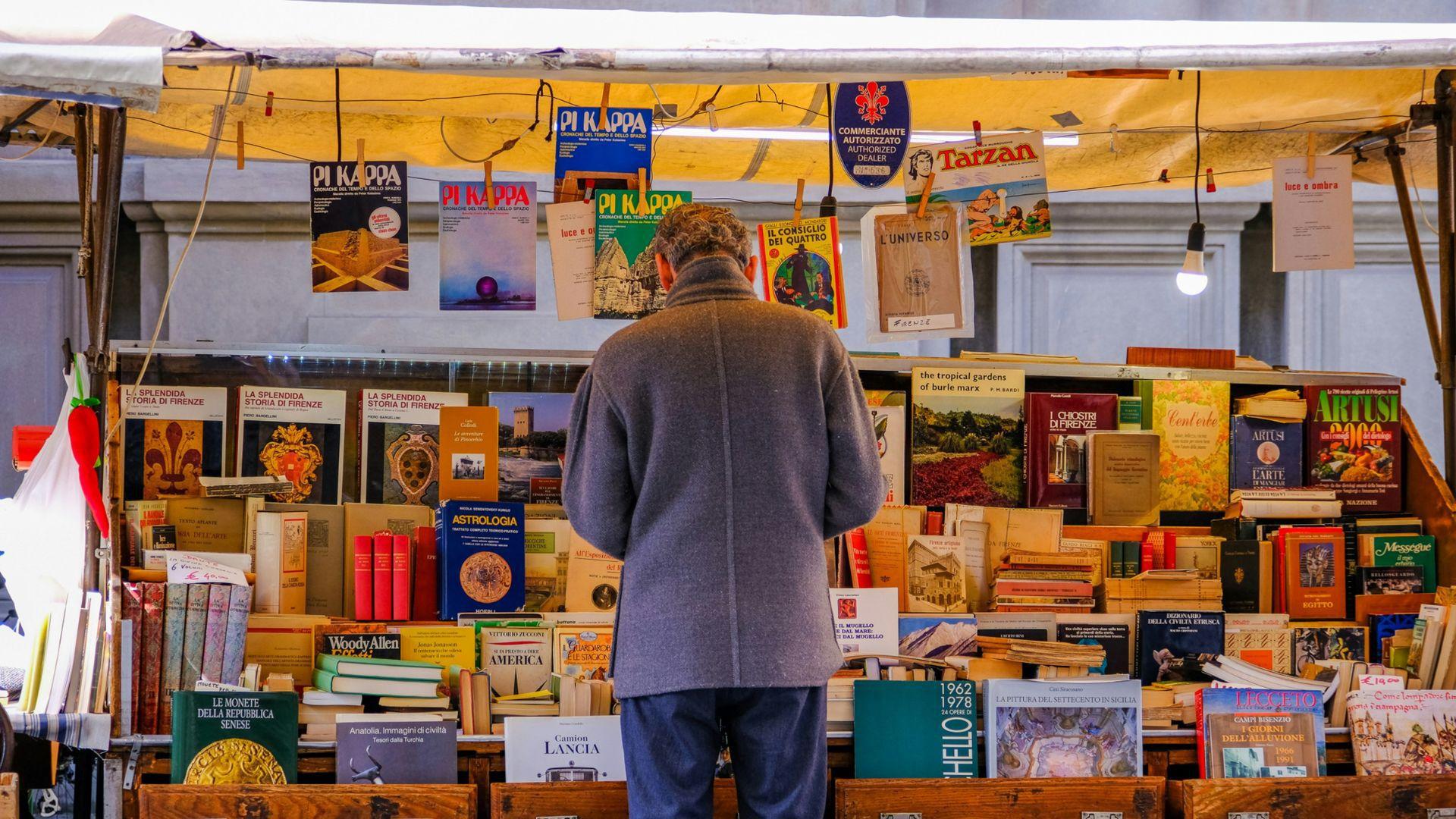 A man standing outside an outdoor book shop on the streets of Florence, Italy.