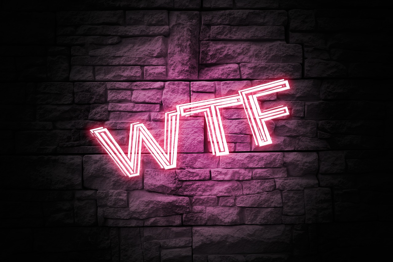 Bright neon sign that says "WTF" on a brick wall in the dark