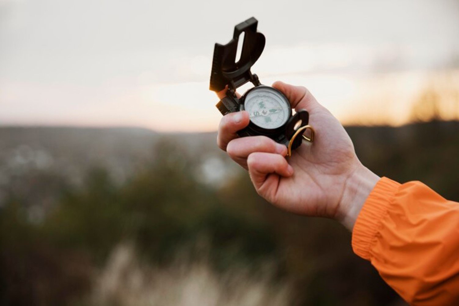 Man in orange jacket using a compass
