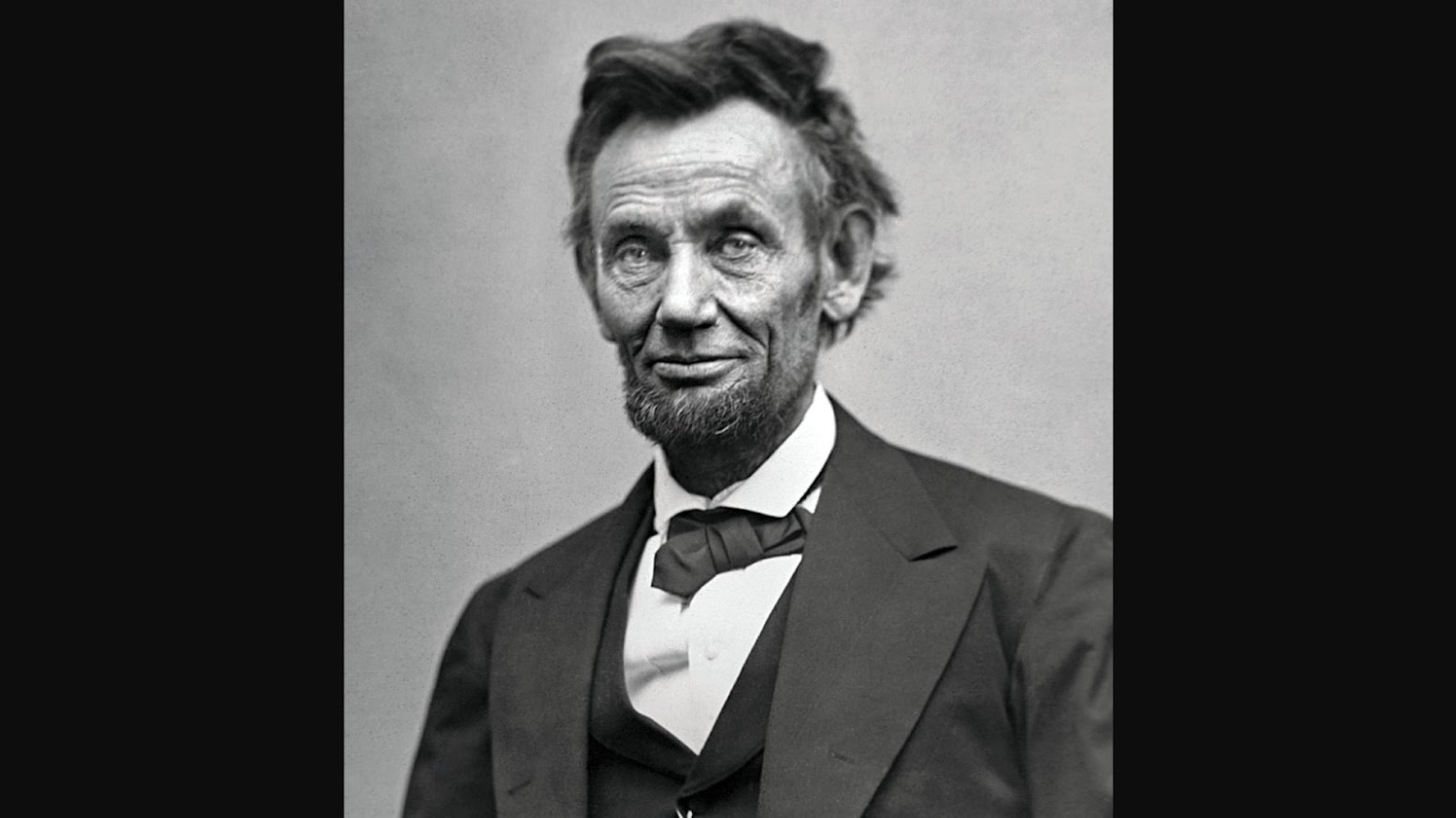 Three-quarter length portrait of Abraham Lincoln seated and holding his spectacles and a pencil just two months before he died in 1865