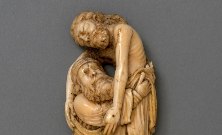 An aged ivory sculpture of a man lowering Jesus from the cross