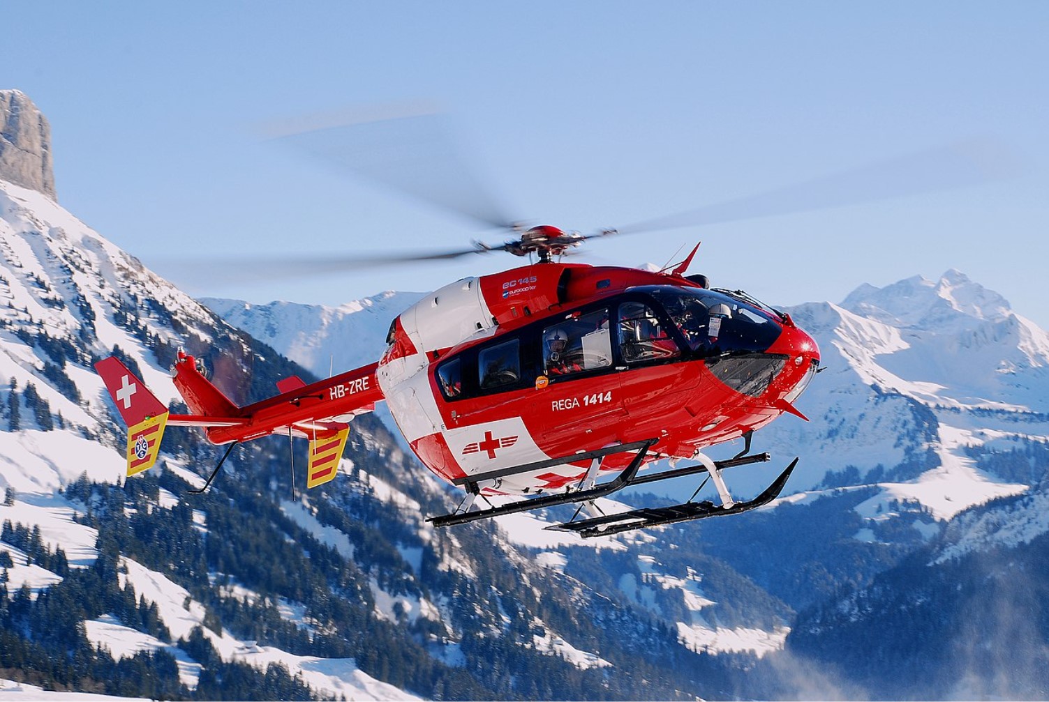 A rescue helicopter is pictured flying over snowy mountains
