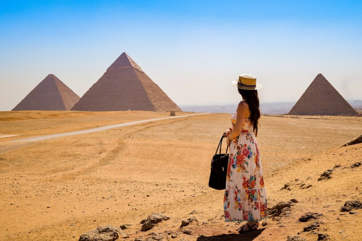 Woman poses in front of the Great Pyramids of Egypt
