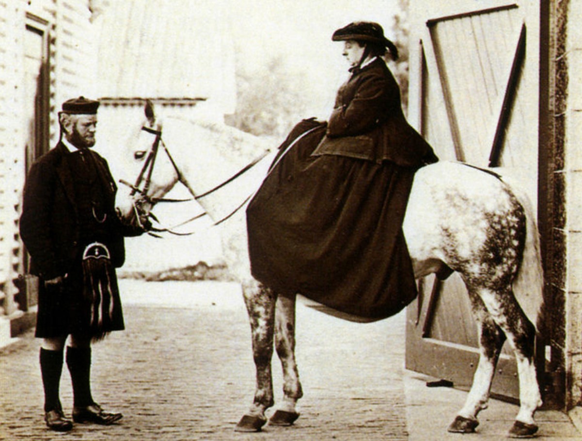 An image of Queen Victoria on a white horse, and by her side stands John Brown.