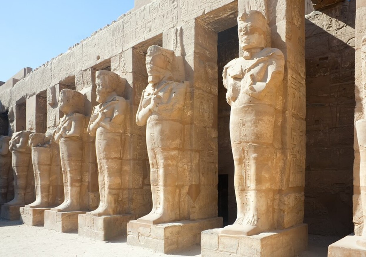 Photograph of statues of Ancient Egypt along the side of a large tomb