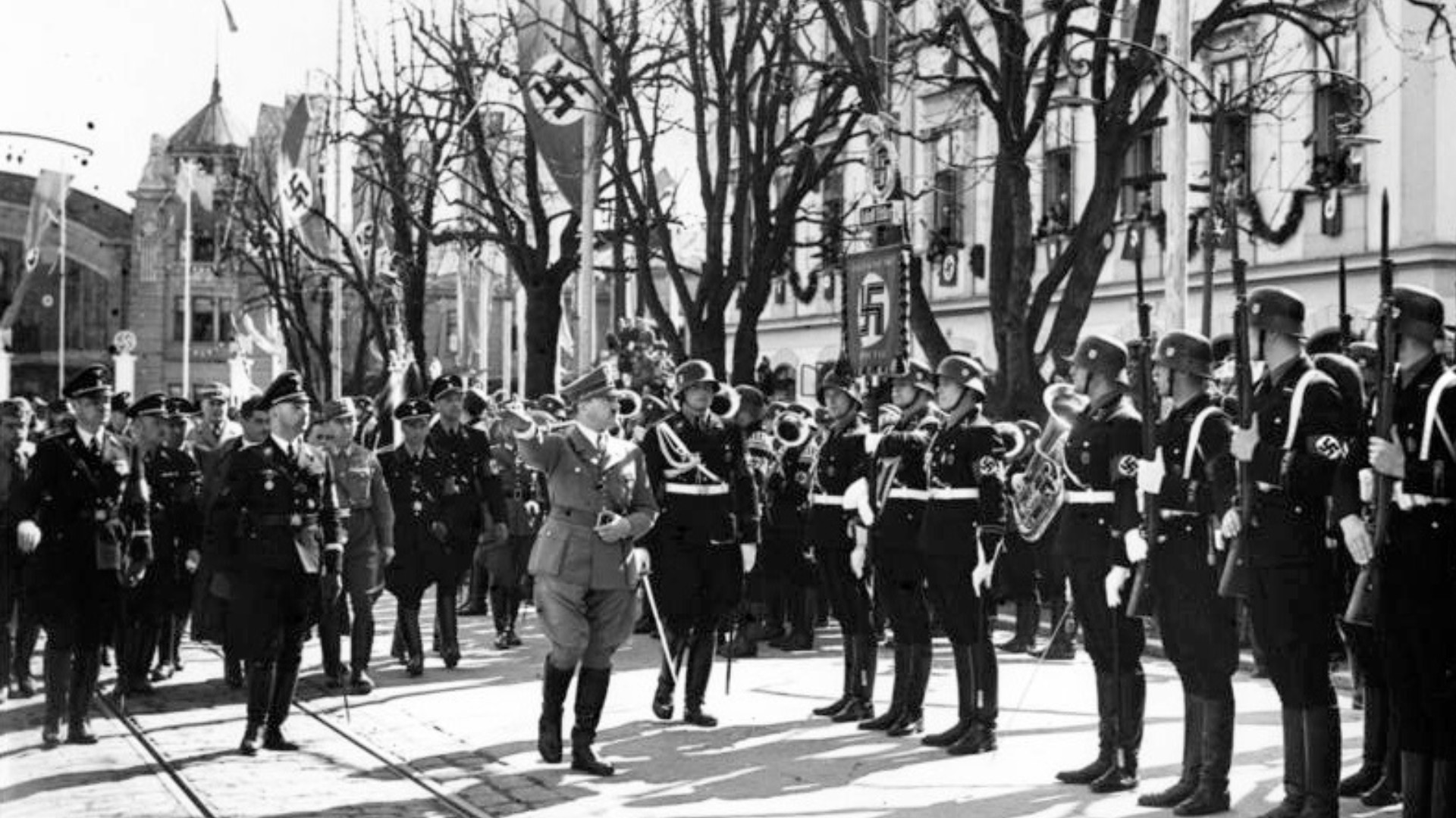 Back-and-white photo of Adolf Hitler and Heinrich Himmler walking before Hitler’s personal bodyguard, the SS Division Leibstandarte.