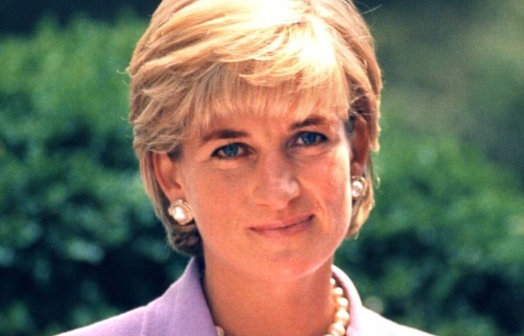 A photograph of Princess Diana dressed in a purple suit and wearing a pearl necklace
