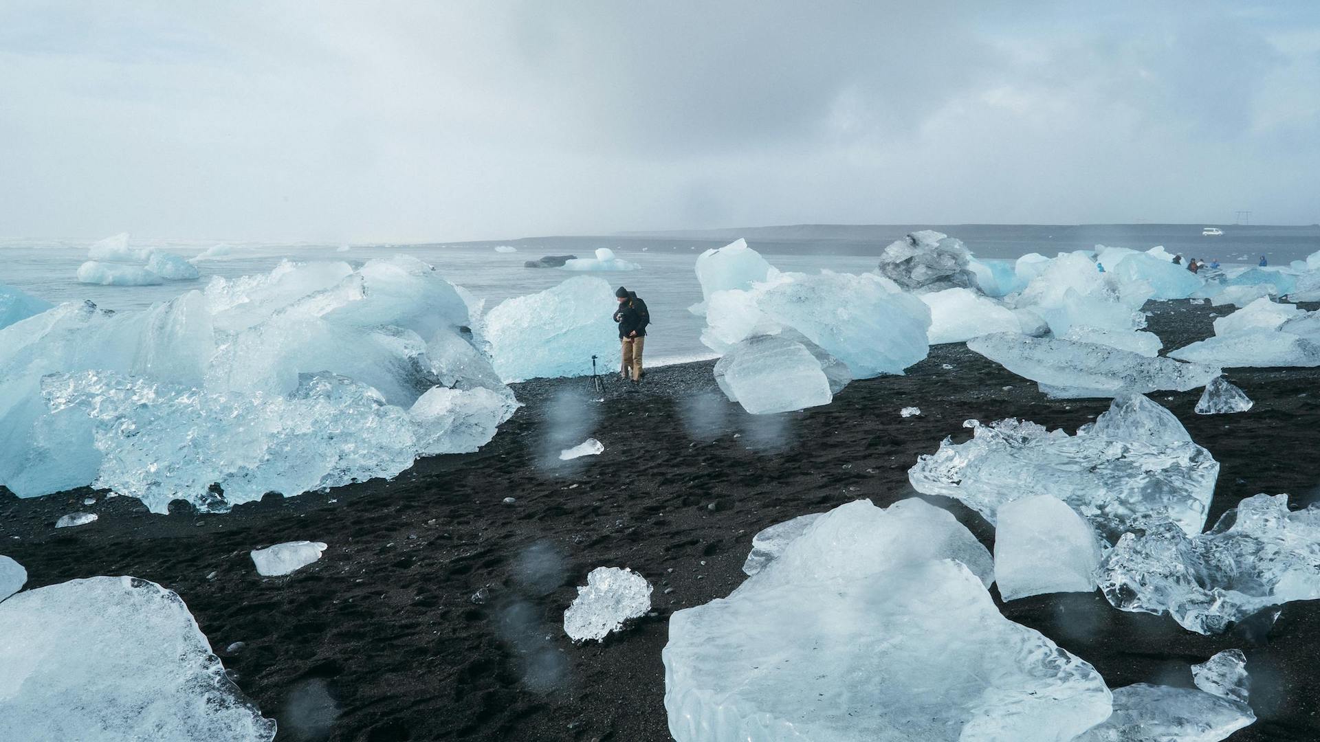 A person standing between large chunks of ice near the ocean
