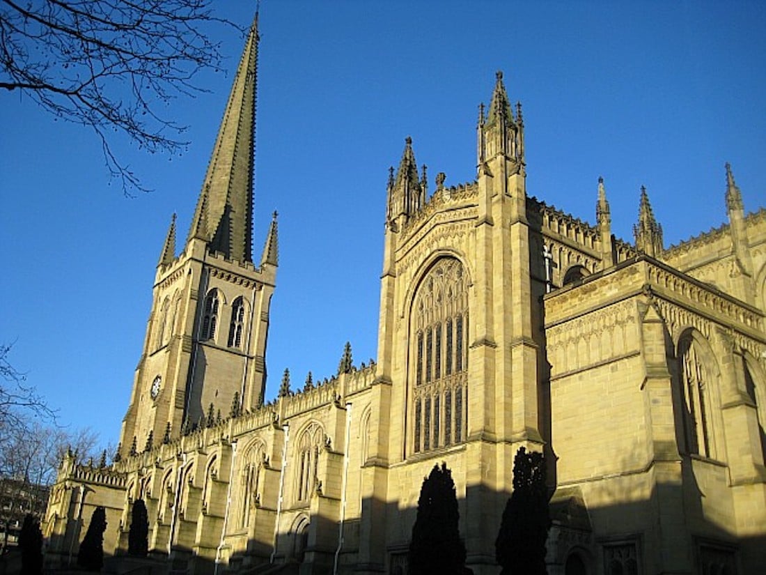 A wide shot of Wakefield cathedral with a bright blue background behind it