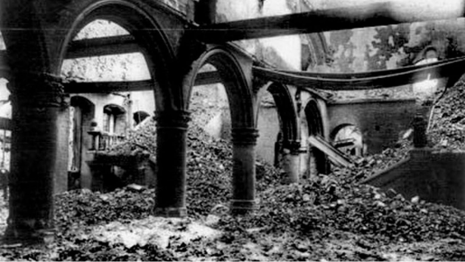 A black and white photo of the Leuven University Library that was destroyed during World War I. Some of the library’s structure is still intact but it is covered in rubble.