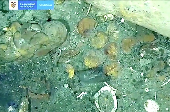 An underwater image of coins in the sand from a shipwreck