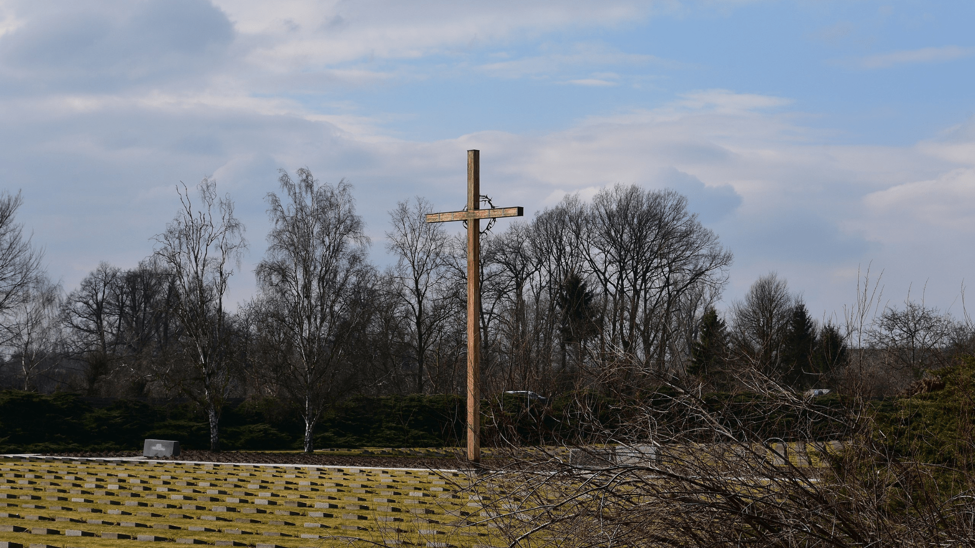 A graveyard with a large wooden cross in it at the Terezin Nazi concentration camp. Photographed in 2016.