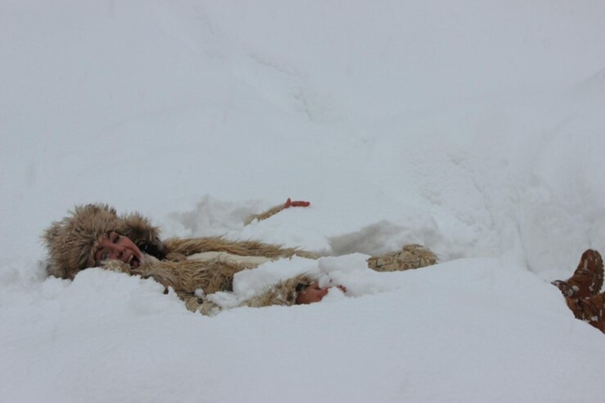 A woman is pictured screaming as she is slowly buried under the snow