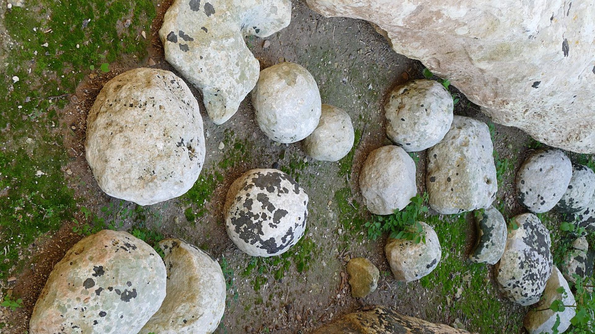 Top-down image showcasing a group of rounded limestone boulders scattered on moss-covered ground. The boulders vary in size and show natural weathering patterns