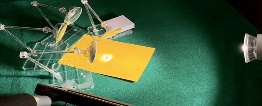 A miniature model of an ancient death ray burning a hole onto a yellow piece of paper