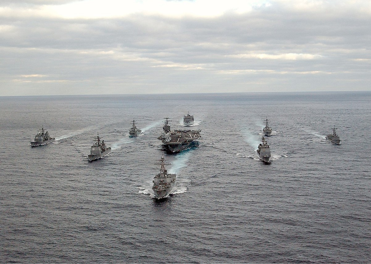 An image of several US Navy ships passing sailing along the ocean