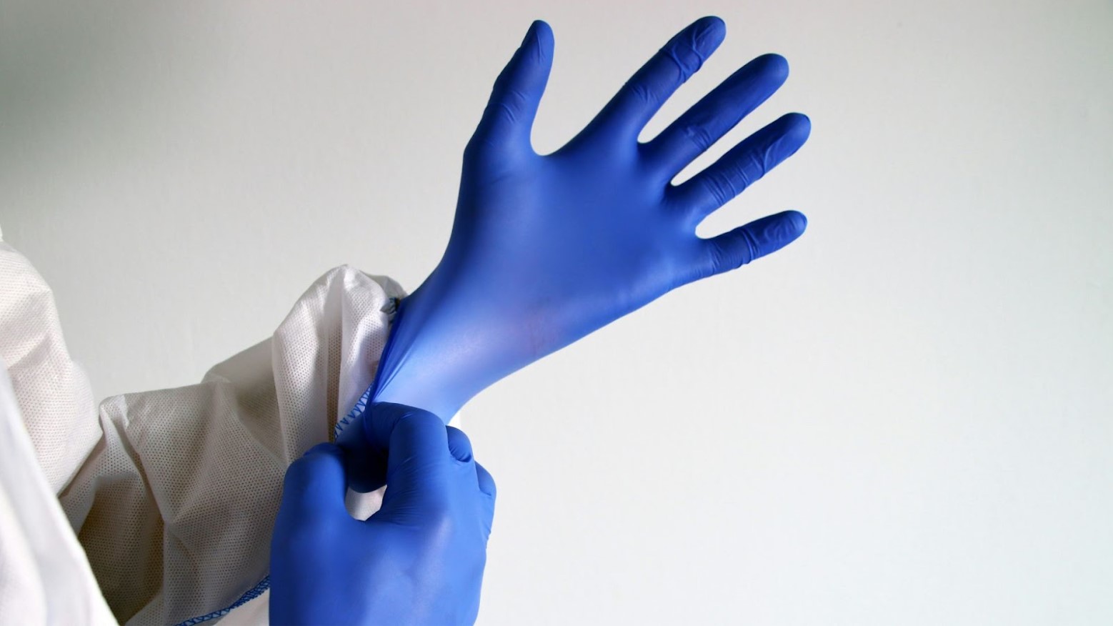 A person putting on blue medical gloves.